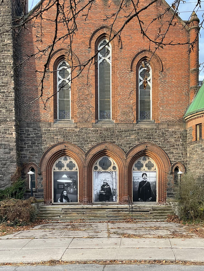 Front facade of church with black and white images installed on the front three doors