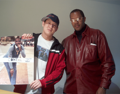 Photographer Jamel Shabazz stands with a fan who is holding a signed CONTACT 2003 poster of Shabazz's image, Rude Boy, Brooklyn, New York, 1982.